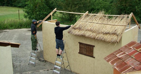 Series co-creator Christopher Dane and volunteer Jack Lewis build one of the village houses